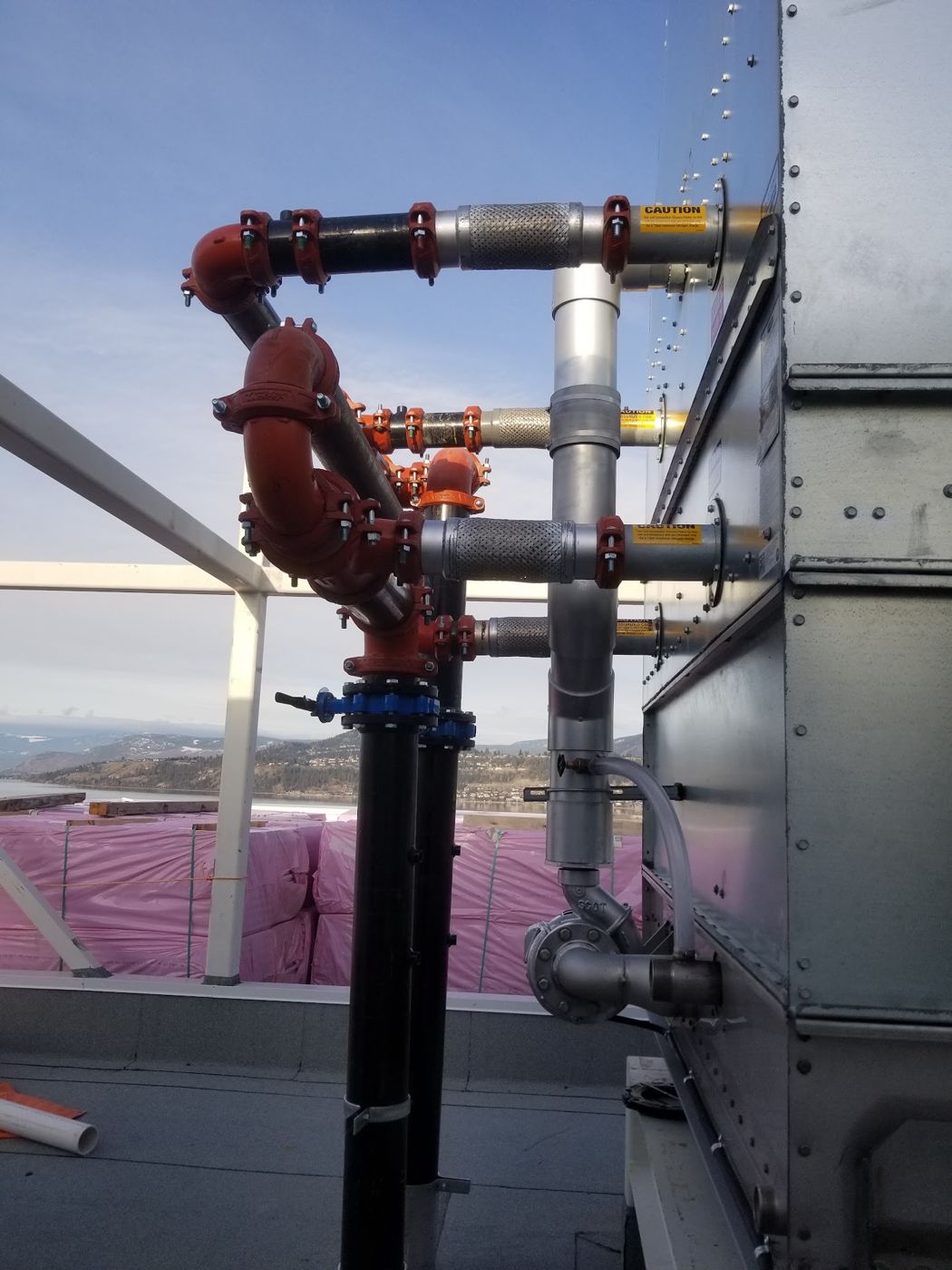 Rooftop mechanical piping install overlooking the valley